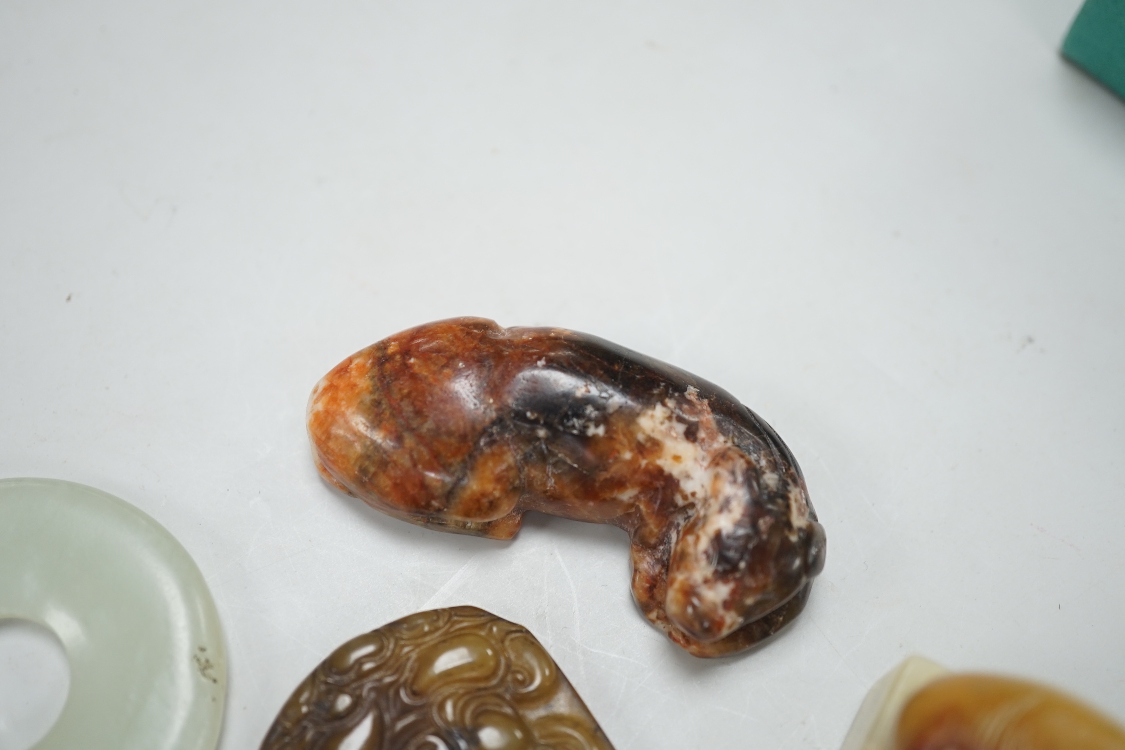 A Chinese pale celadon jade bi disc, a jade carving of the character ‘Shou’ , two hardstone carvings of creatures, an agate pendant of Guanyin in Tang dynasty style and a stained glass , bead in Tibetan style (6), disc 4
